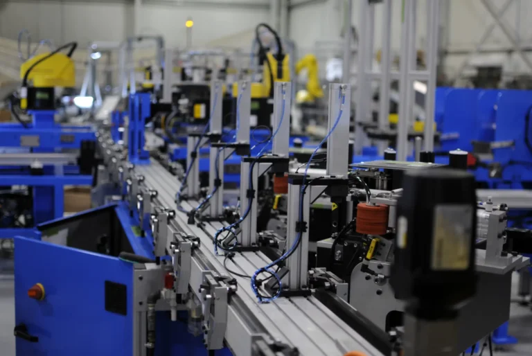 Modern industrial automation assembly line with interconnected robotic machinery, conveyor belts, and advanced manufacturing components in a high-tech factory setting.