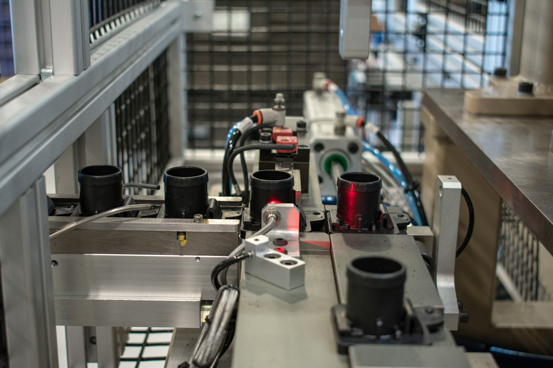 Inline feeder track with drain connectors ready to be loaded into a spin weld station