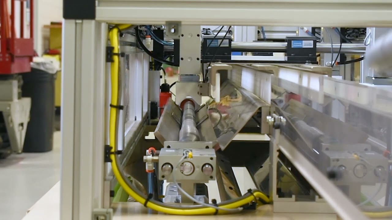Automated machinery with tubing and sensors on a production line. Features include tubing, sensors, and robotic arms.