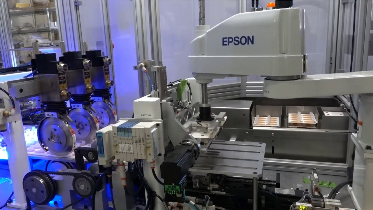 A high-precision Epson industrial robotic arm operating in an automated manufacturing setup, assembling components with various mechanical components.