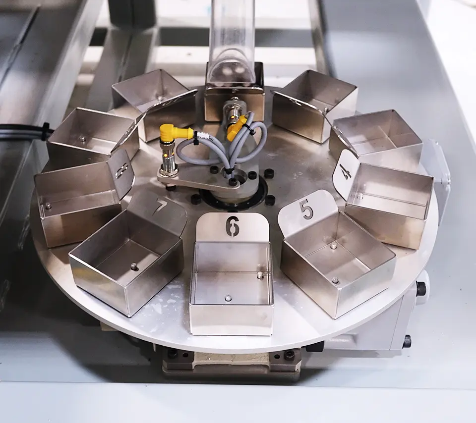 Metal numbered trays on a round rotary table with a yellow and gray wired component in the center.