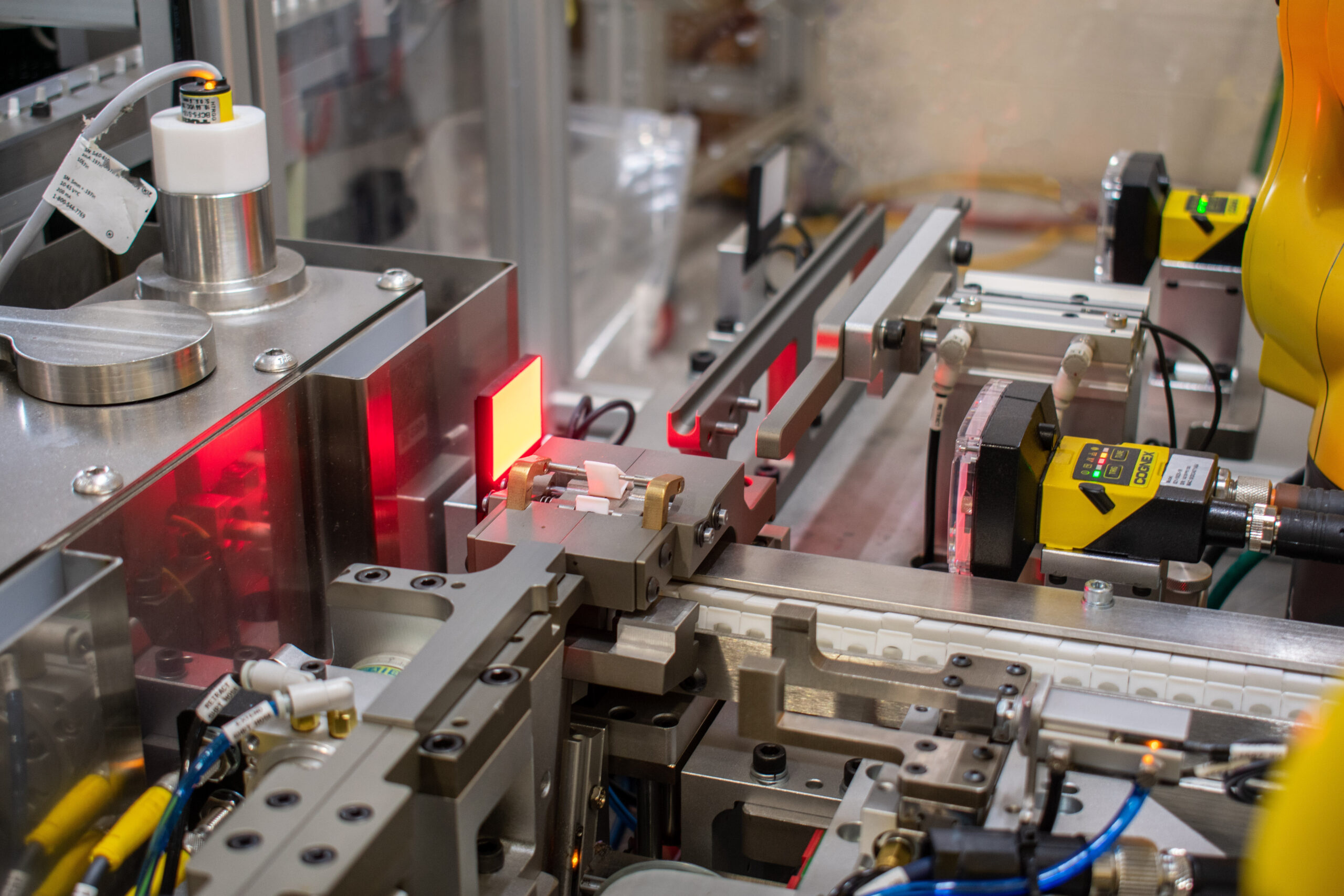 Automated assembly line with sensors and mechanical arms. Red light highlights the process.