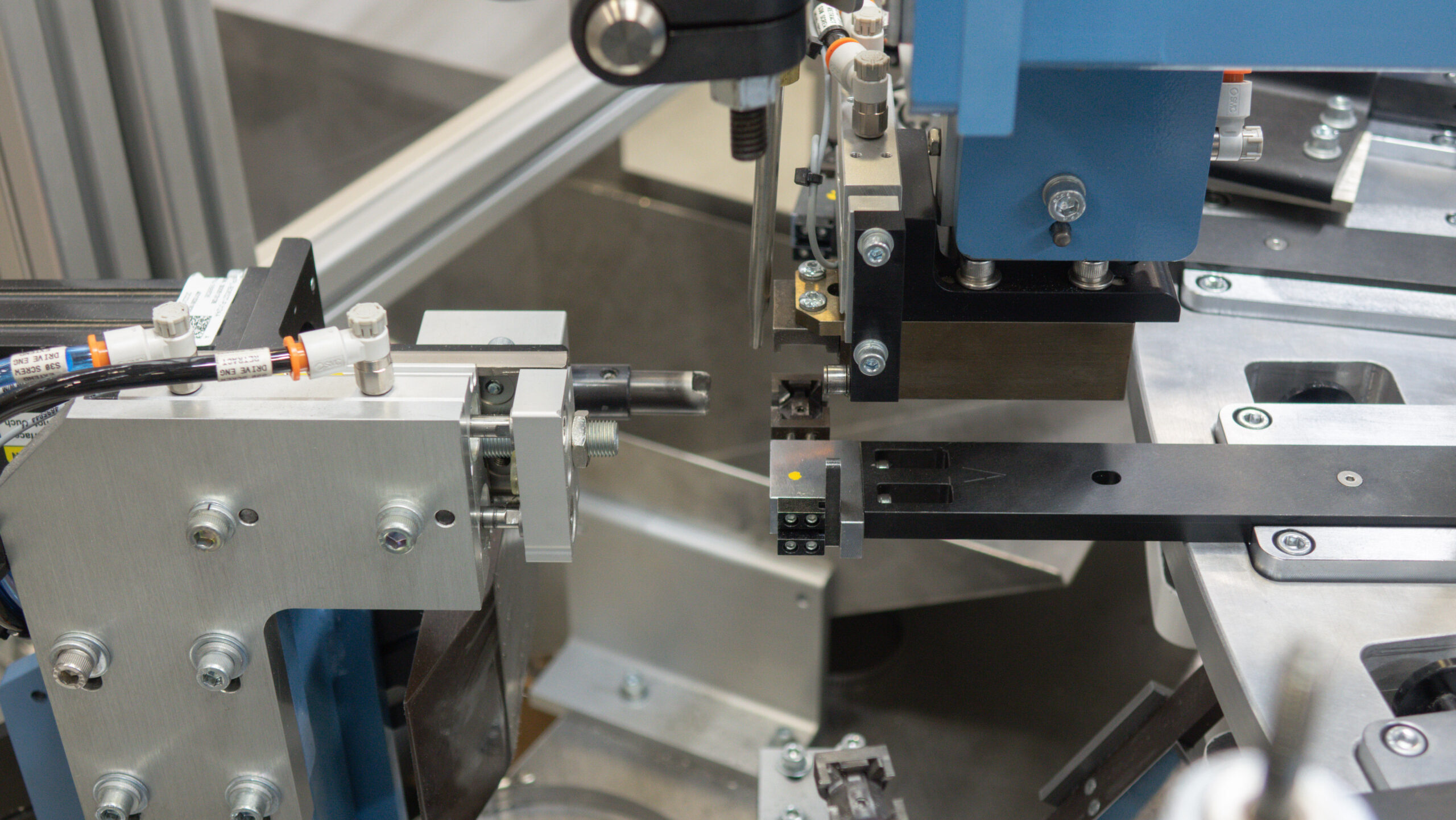 The machine features pneumatic fittings and a clamping mechanism, focused on a central point where a component is likely being processed.