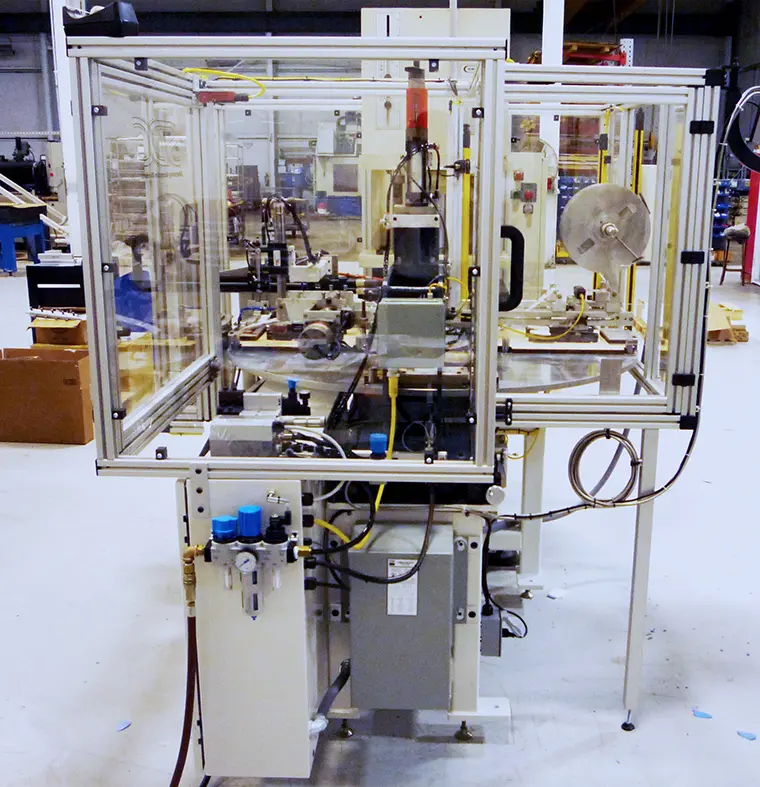 Machine features a two-part design with clear acrylic enclosures supported by a silver metal frame. Within the enclosures, one can see various mechanical components, including sensors, actuators, and wiring.