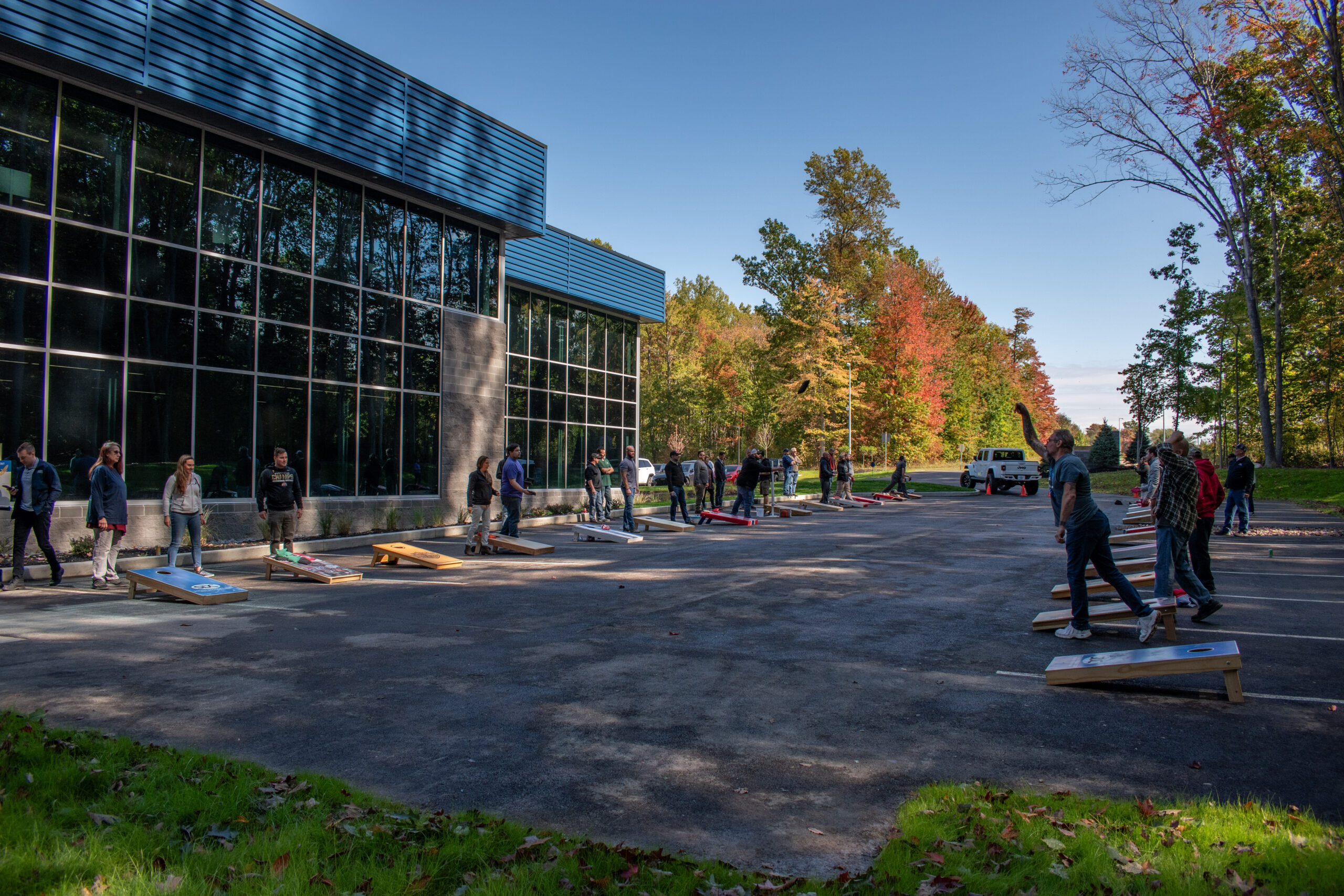 Cornhole game outdoors. People playing cornhole in corporate parking lot during autumn.