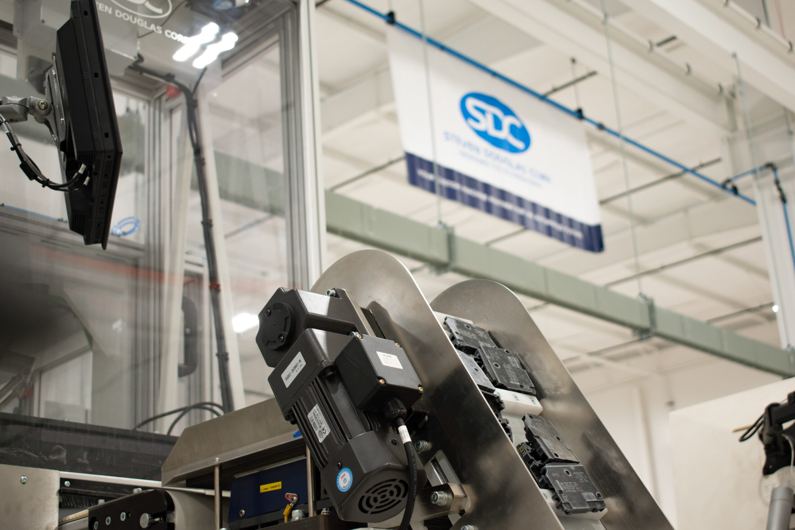 Bottom-up view of a part conveyor with the SDC shop banner in the background