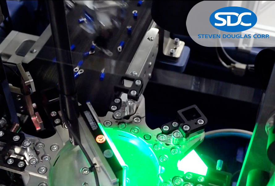 Electronics Mini Video Thumbnail showing end connectors on a conveyor being loaded onto an automated machine with a green light