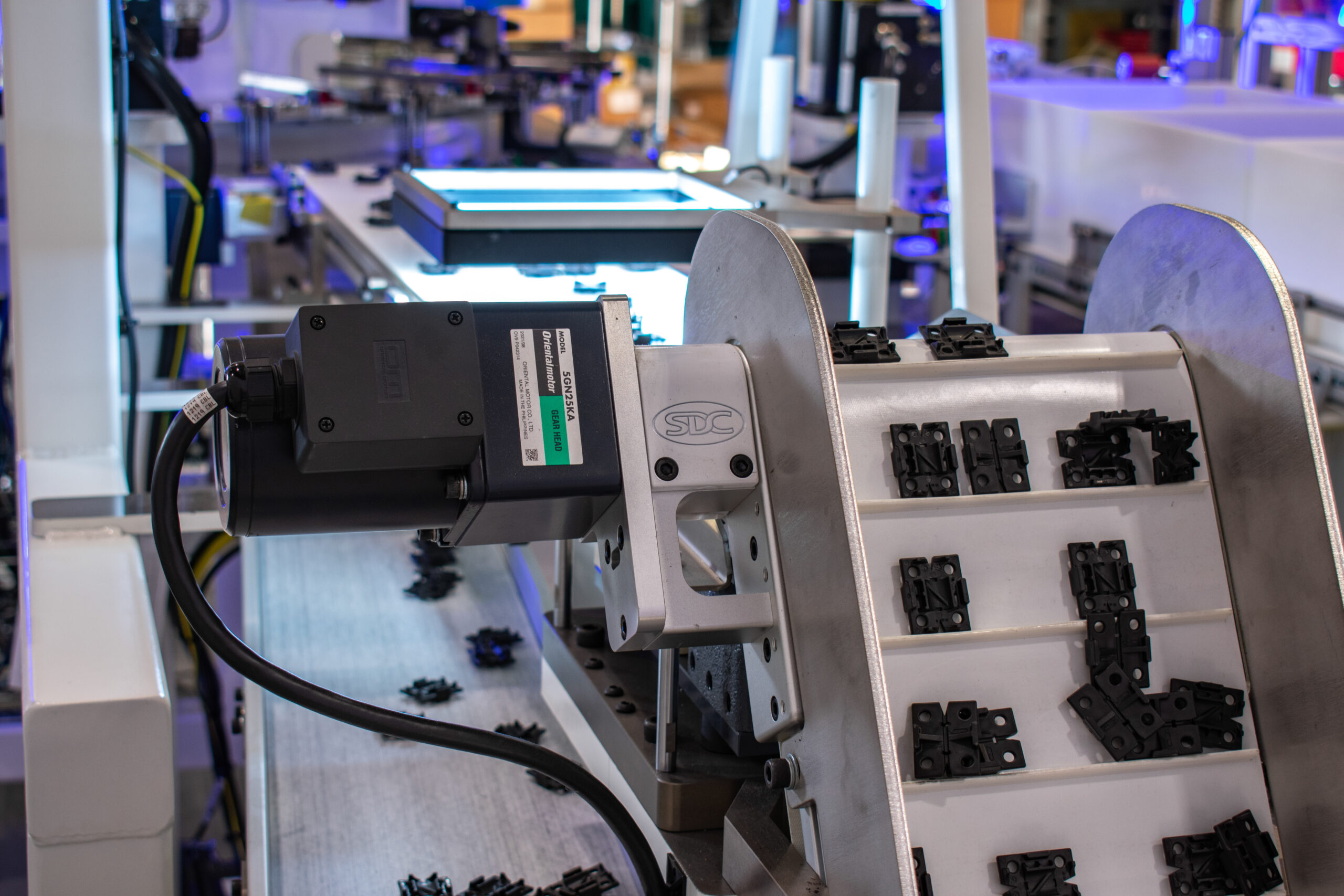Automated assembly line with black components moving on a conveyor.