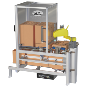 A Steven Douglas Corp (SDC) robotic packaging machine encloses a series of cardboard boxes in a metal frame with clear plastic sides.