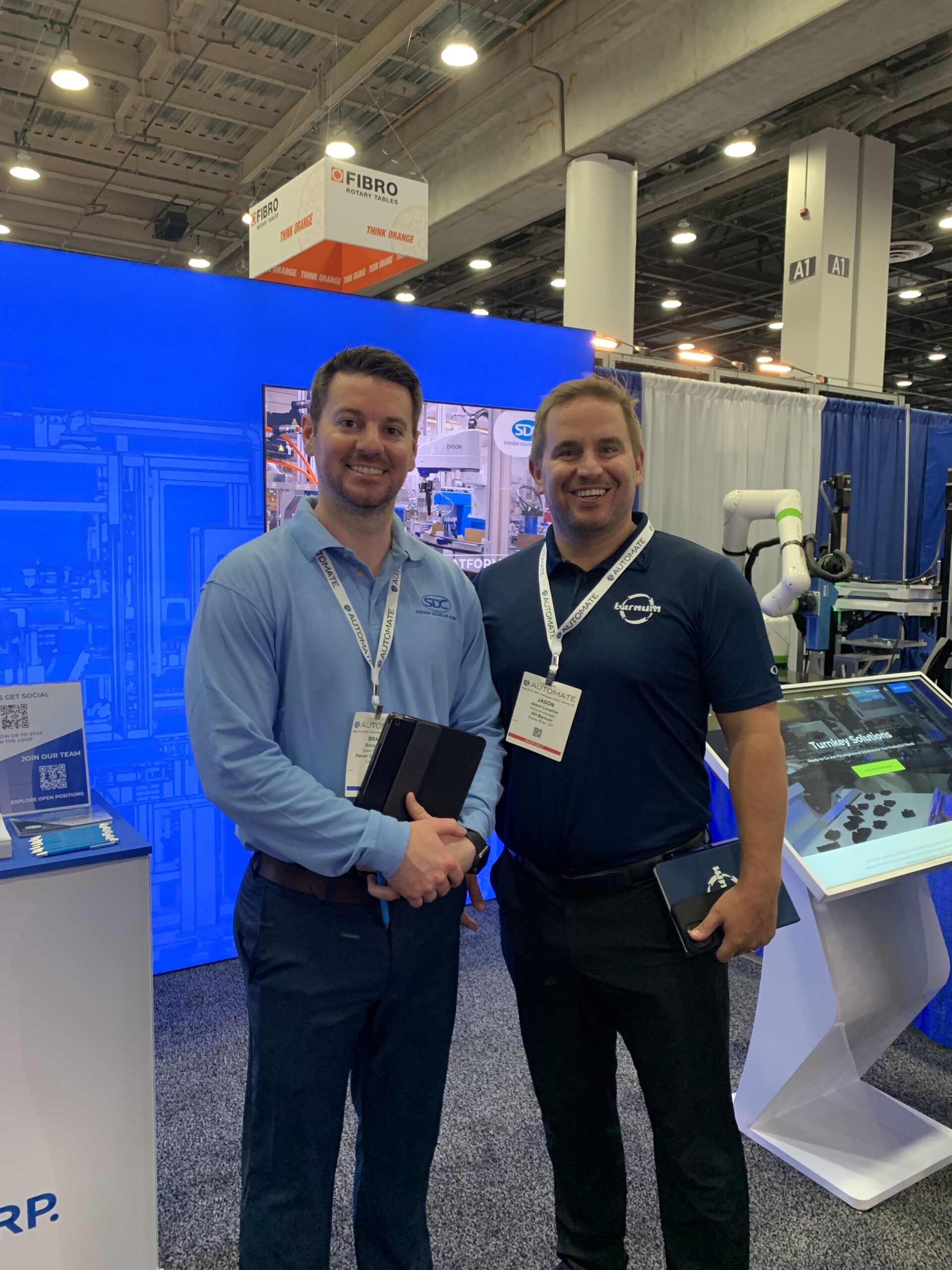 An SDC booth member posing with a Barnum rep at Automate