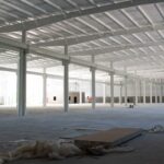 Inside of machine shop while it was being built with just outside sun light shining in.
