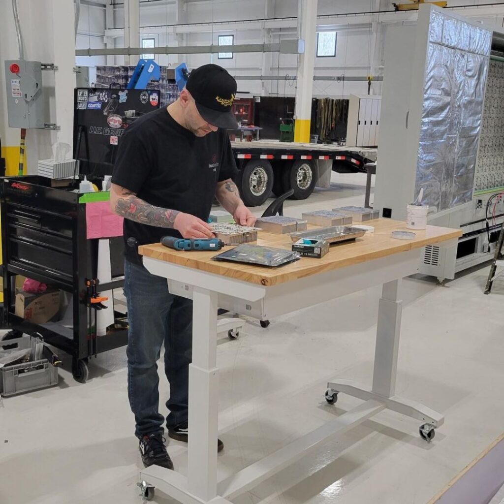 Engineer with baseball hat looking down and measuring a component.