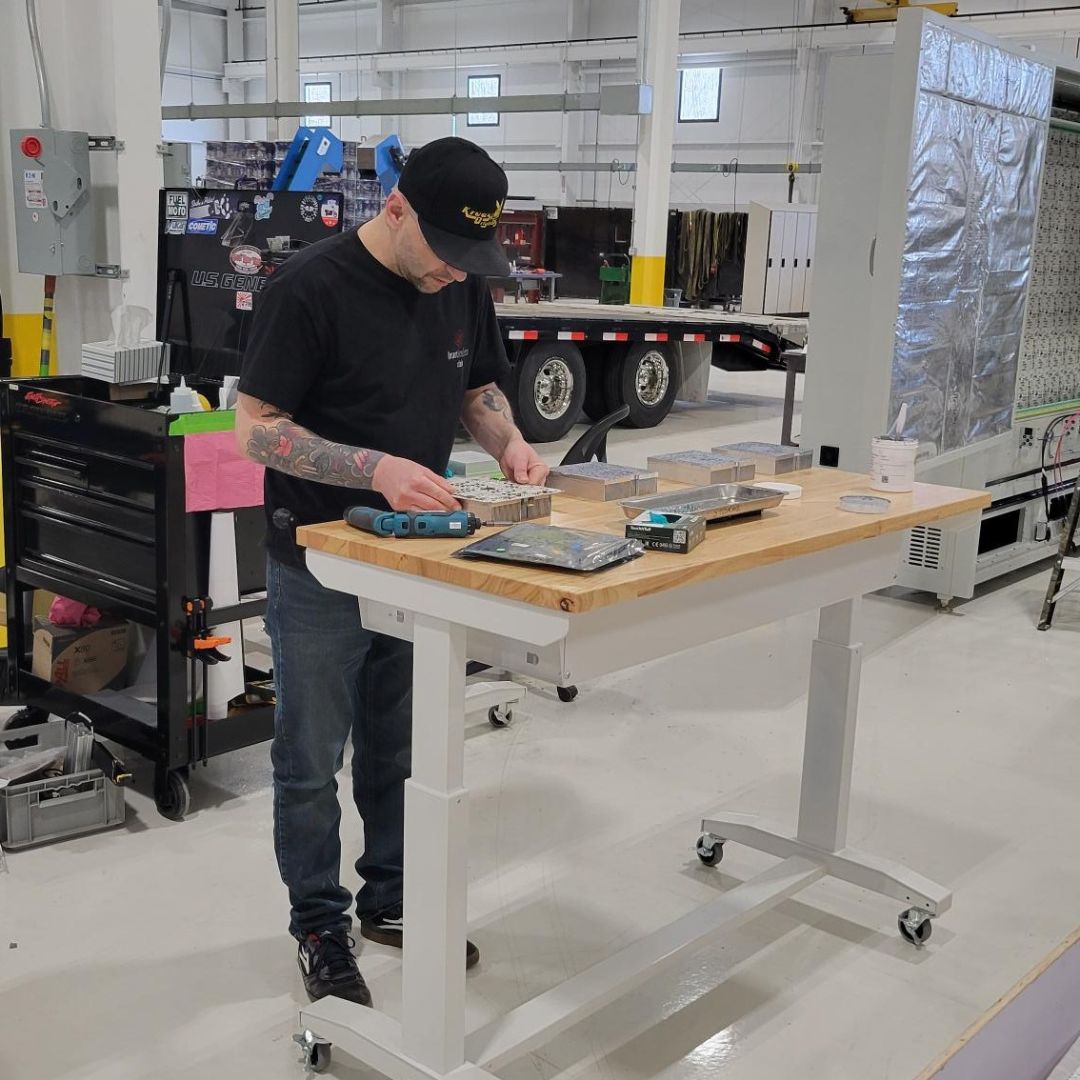 Technician with baseball hat looking down and measuring a component.