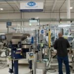 Engineer working on a machine with the SDC flag in the background.