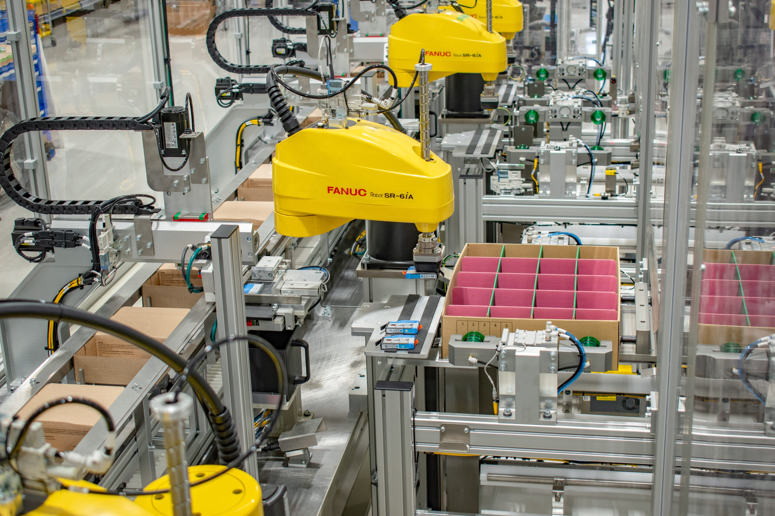 Assembly line of FANUC robots performing an automated packaging process with custom SDC technology