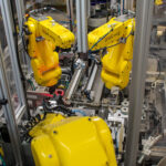 Three 6-axis FANUC robotic arms integrated onto a medical device assembly machine