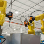 Three Synchronous FANUC robots with ATI end effectors for an automated deflashing process.