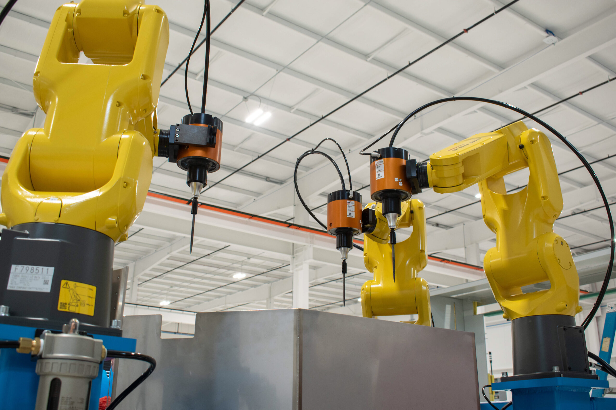 Three Synchronous FANUC robots with ATI end effectors for an automated deflashing process.