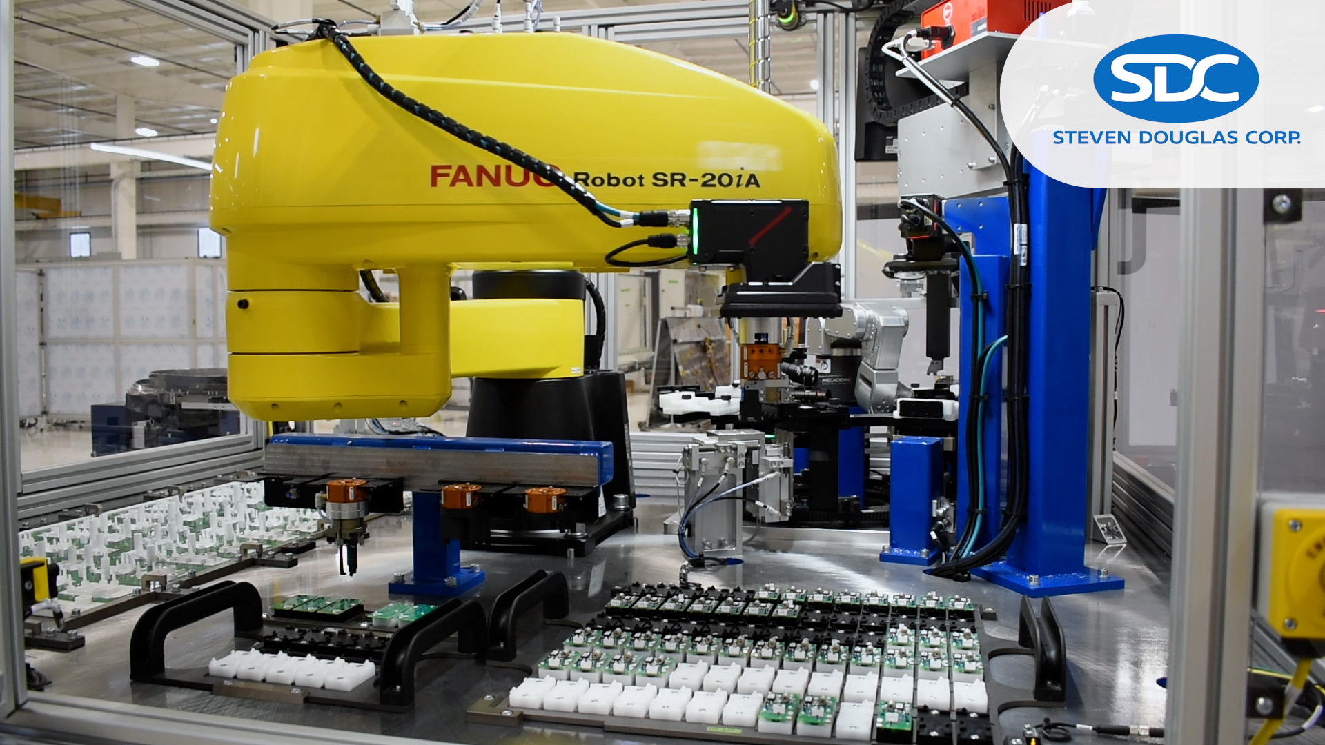 YouTube video thumbnail with a FANUC SCARA robot, infeed trays of boards, and a mini indexing table in the background