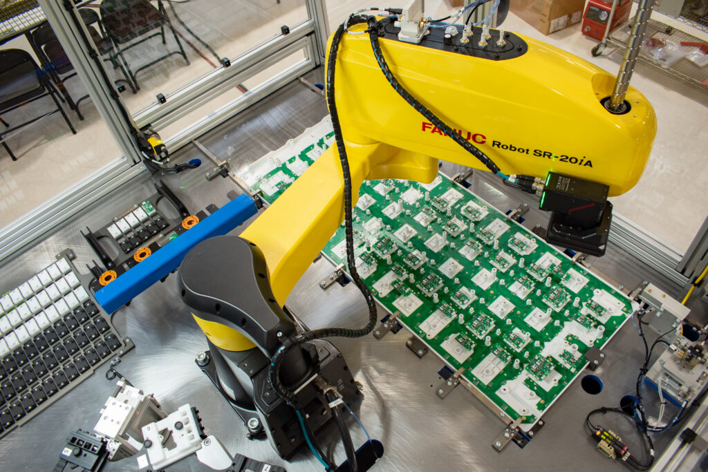 FANUC SCARA robot positioned over a circuit board former tray with a Keyence camera mounted on it.